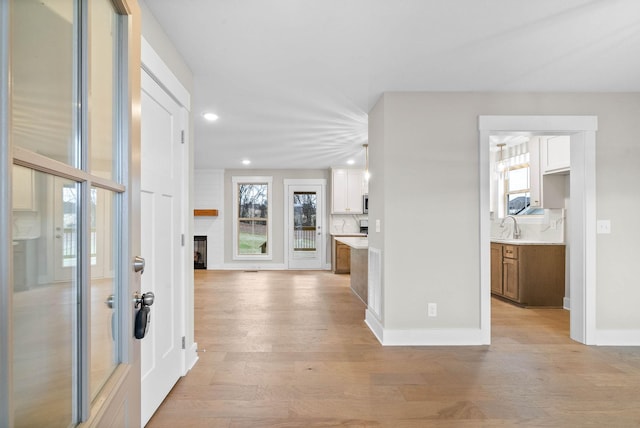 entrance foyer with light wood-type flooring, a fireplace, baseboards, and recessed lighting