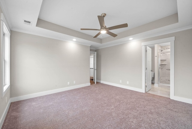 empty room featuring light carpet, visible vents, a tray ceiling, and ornamental molding