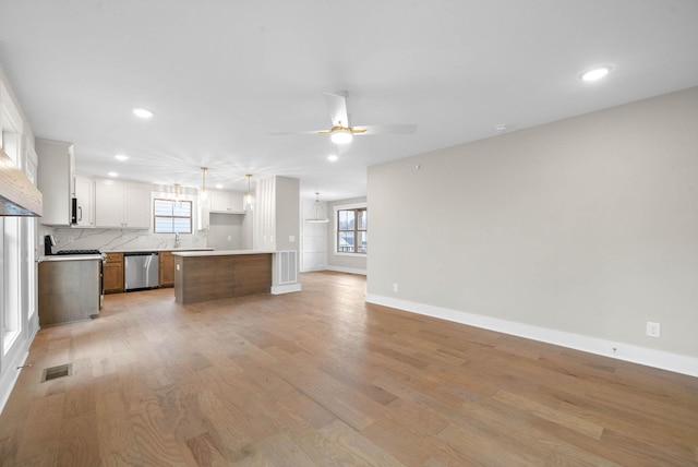 kitchen featuring a center island, stainless steel appliances, light countertops, open floor plan, and white cabinets