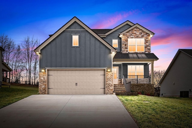 view of front of home with driveway, central AC unit, a lawn, stone siding, and board and batten siding