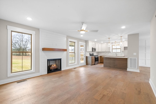 unfurnished living room with light wood-type flooring, a large fireplace, visible vents, and recessed lighting