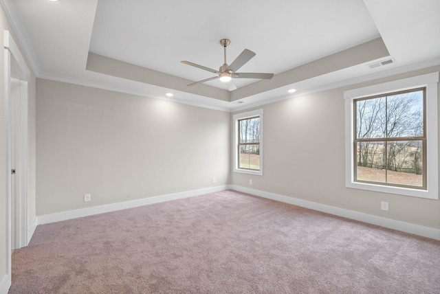 unfurnished room with light carpet, baseboards, visible vents, and a raised ceiling