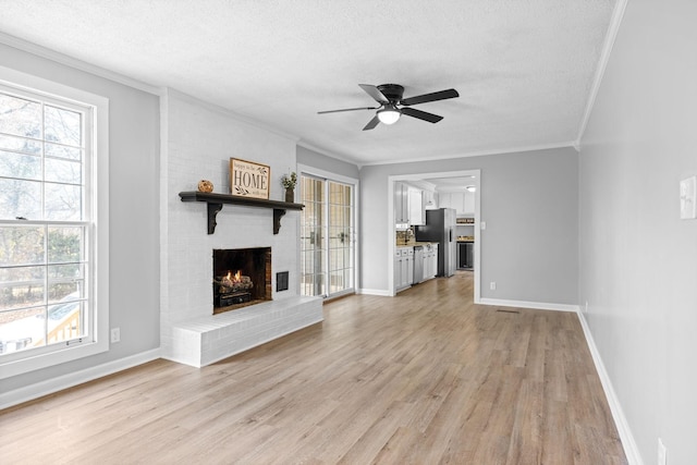 unfurnished living room with light wood-type flooring, a fireplace, a textured ceiling, and plenty of natural light