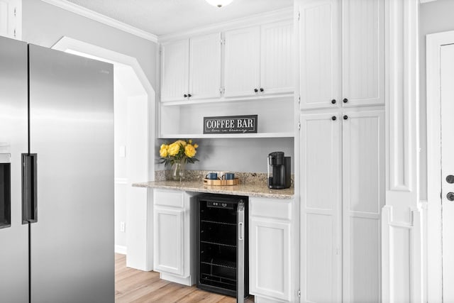 kitchen featuring stainless steel fridge, white cabinetry, ornamental molding, light hardwood / wood-style floors, and beverage cooler