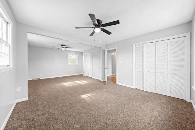 unfurnished bedroom with carpet floors, two closets, and ceiling fan