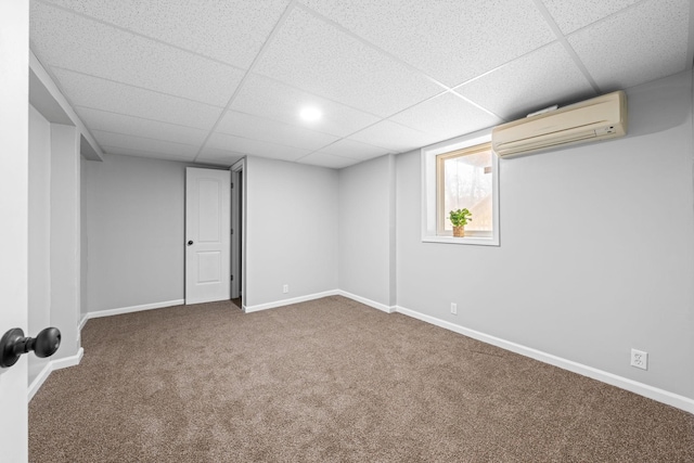 basement with a paneled ceiling, a wall mounted AC, and carpet