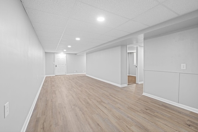 basement featuring a paneled ceiling and light wood-type flooring