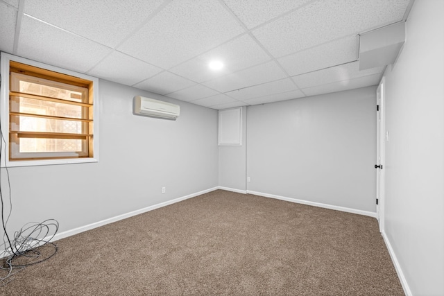 basement featuring carpet floors, a drop ceiling, and a wall unit AC