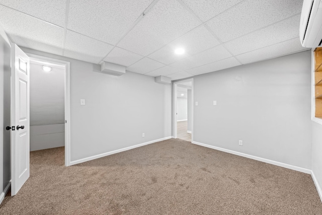 basement featuring carpet, a wall mounted AC, and a paneled ceiling