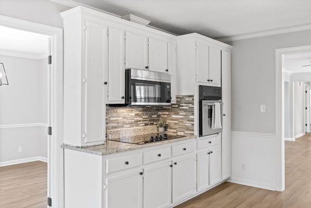 kitchen with white cabinetry, appliances with stainless steel finishes, crown molding, and light hardwood / wood-style flooring