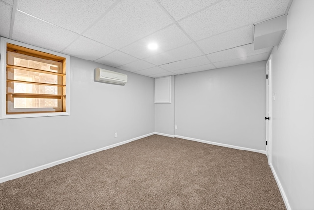 basement featuring a drop ceiling, a wall mounted air conditioner, and carpet flooring