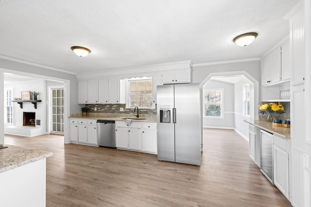 kitchen with stainless steel appliances, sink, white cabinets, and light hardwood / wood-style floors