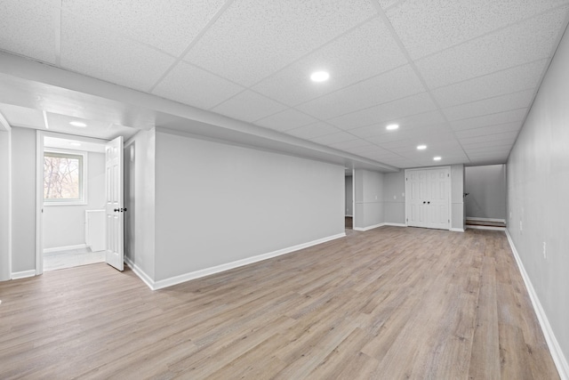 basement with a drop ceiling and light hardwood / wood-style floors