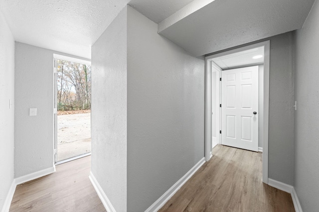 hallway with light hardwood / wood-style flooring and a textured ceiling