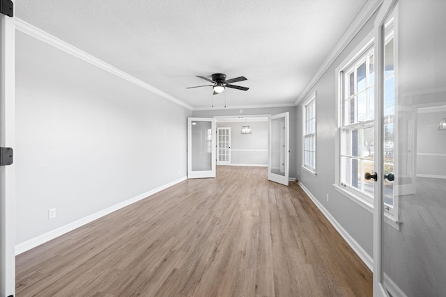 unfurnished living room with crown molding, light hardwood / wood-style floors, ceiling fan, and french doors