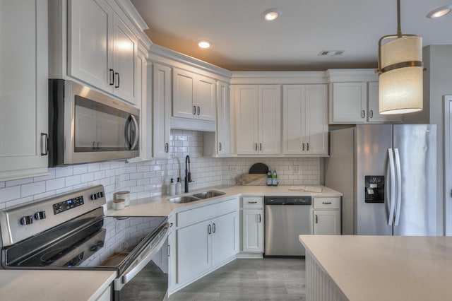 kitchen featuring appliances with stainless steel finishes, sink, white cabinets, and decorative light fixtures