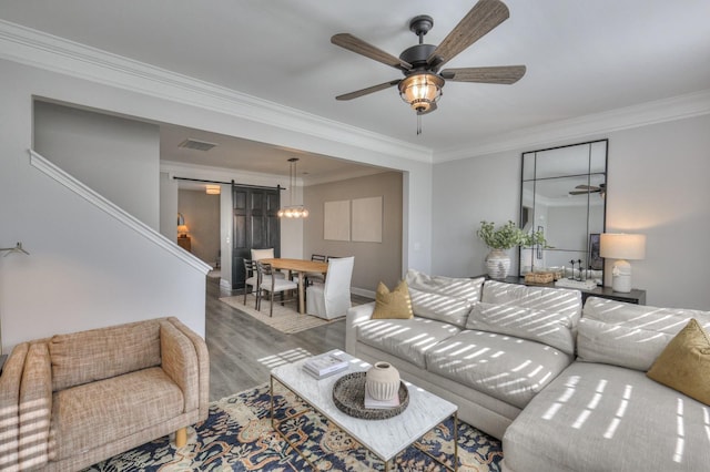 living room with ornamental molding, a barn door, hardwood / wood-style floors, and ceiling fan