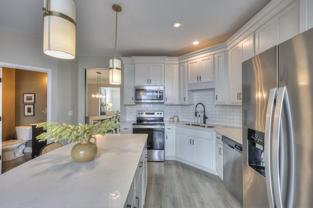 kitchen featuring sink, white cabinets, backsplash, hanging light fixtures, and stainless steel appliances