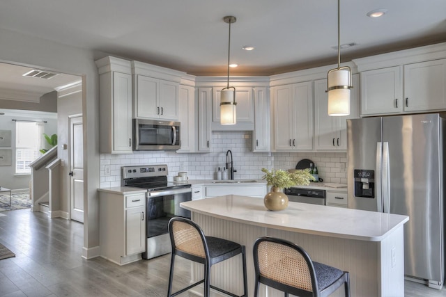 kitchen with pendant lighting, appliances with stainless steel finishes, sink, and a kitchen island