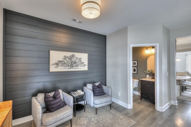 sitting room featuring hardwood / wood-style flooring and wood walls