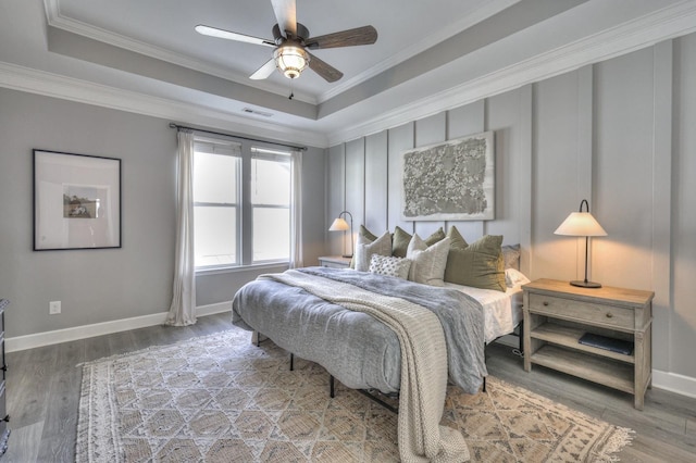 bedroom featuring hardwood / wood-style flooring, ceiling fan, crown molding, and a raised ceiling