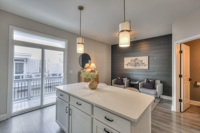 kitchen with pendant lighting, white cabinetry, light hardwood / wood-style floors, and a kitchen island