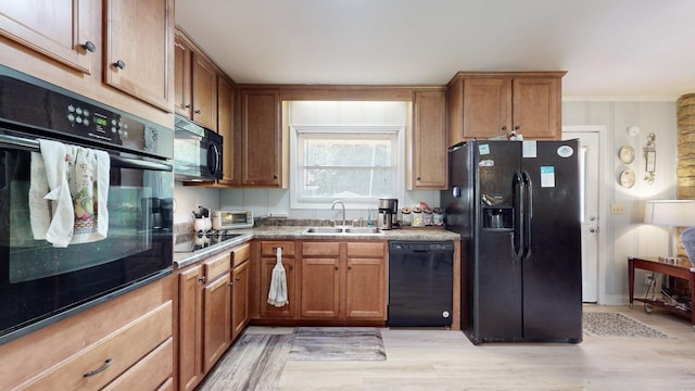 kitchen featuring sink, light hardwood / wood-style flooring, and black appliances