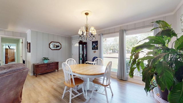 dining room with crown molding, an inviting chandelier, and light hardwood / wood-style floors