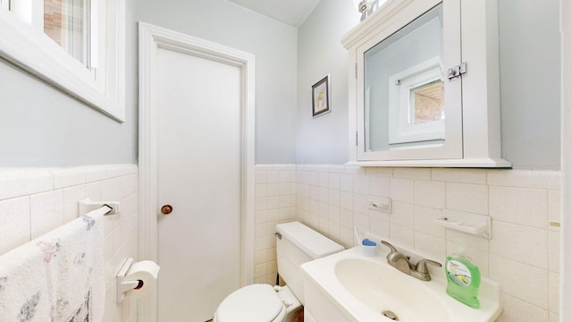 bathroom with toilet, sink, and tile walls