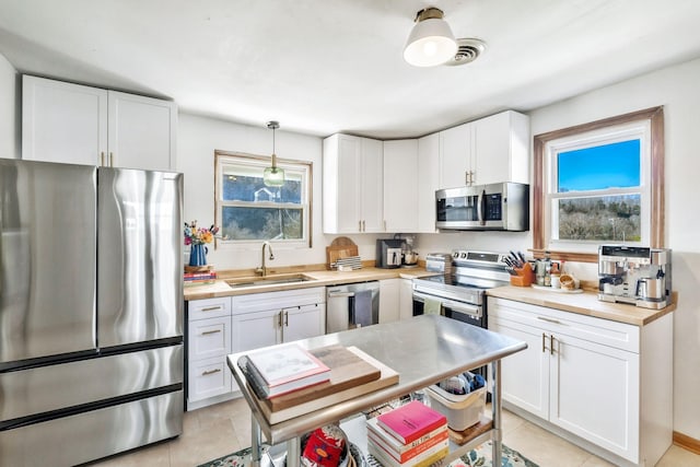 kitchen with white cabinetry, appliances with stainless steel finishes, sink, and hanging light fixtures