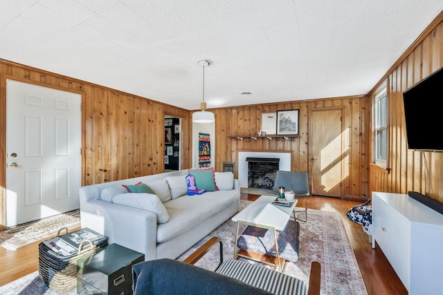 living room with a brick fireplace, hardwood / wood-style floors, and wood walls