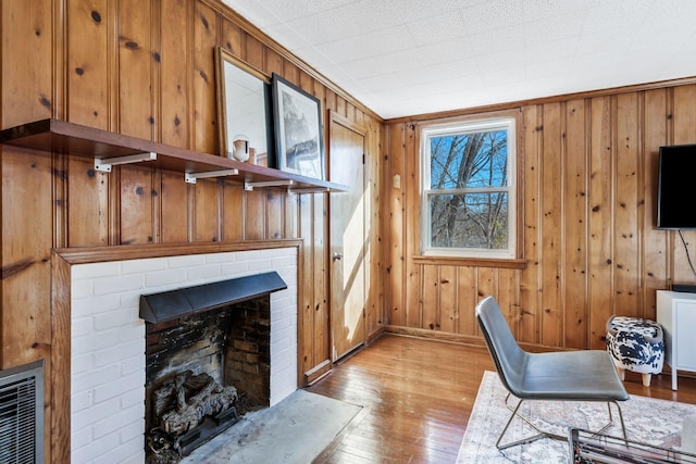 office space featuring heating unit, light hardwood / wood-style floors, a brick fireplace, and wood walls