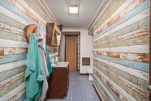 bathroom with toilet, vanity, wooden walls, and a textured ceiling