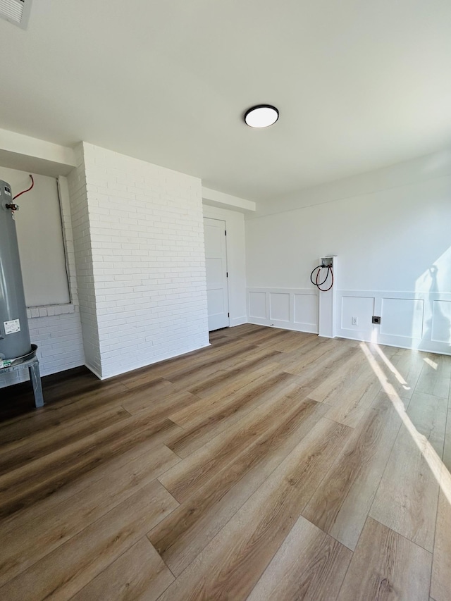 spare room with hardwood / wood-style flooring and brick wall