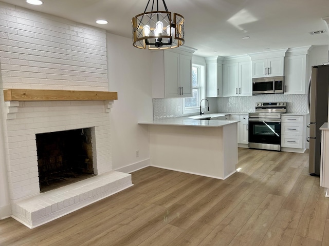 kitchen featuring white cabinetry, appliances with stainless steel finishes, kitchen peninsula, and light hardwood / wood-style floors