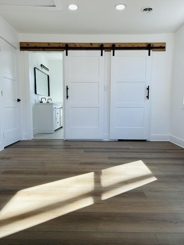 interior space with a barn door and dark wood-type flooring