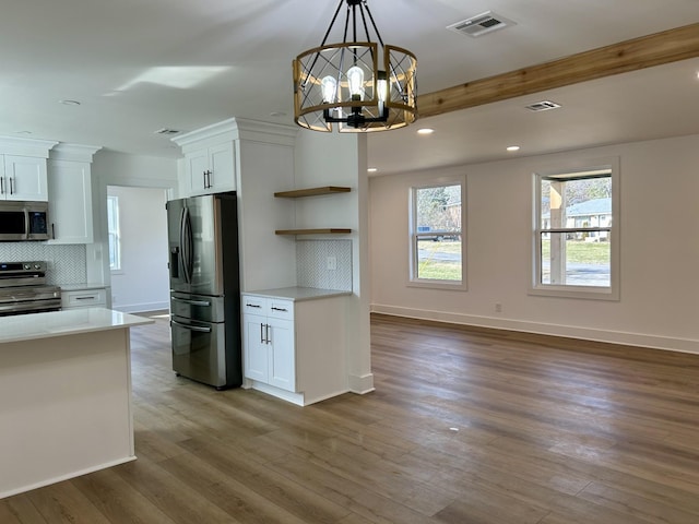 kitchen featuring dark wood-type flooring, white cabinetry, tasteful backsplash, decorative light fixtures, and appliances with stainless steel finishes