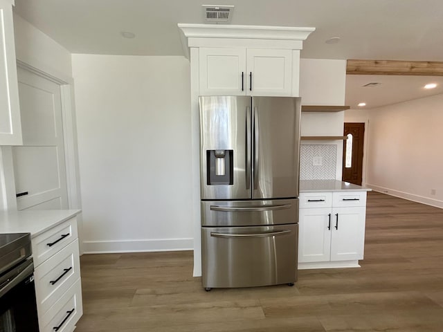 kitchen featuring stove, stainless steel fridge, light hardwood / wood-style flooring, and white cabinets