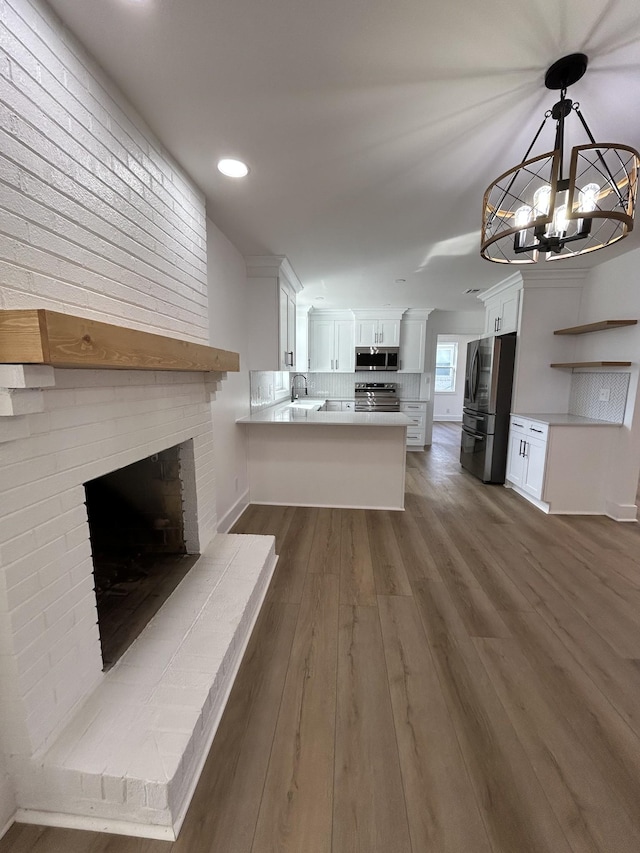 kitchen featuring appliances with stainless steel finishes, hanging light fixtures, white cabinets, dark hardwood / wood-style flooring, and kitchen peninsula