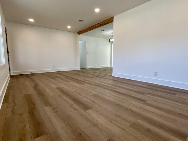 spare room with light hardwood / wood-style flooring and beamed ceiling