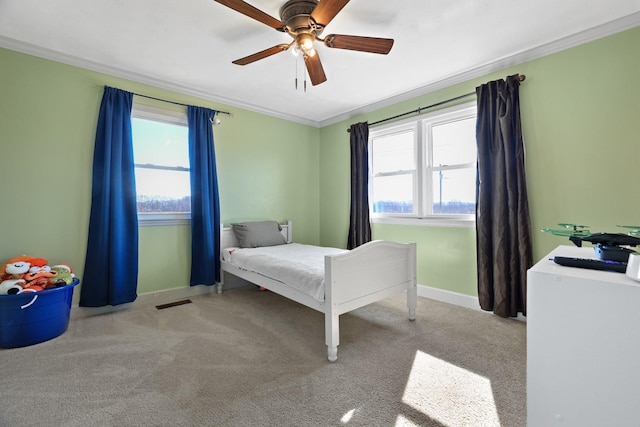 carpeted bedroom with ceiling fan, ornamental molding, and multiple windows