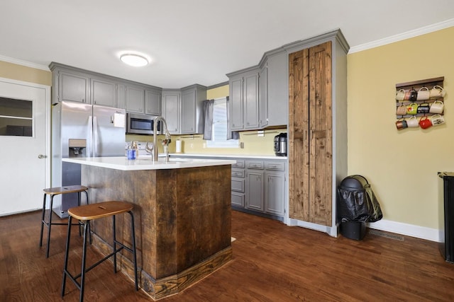 kitchen with crown molding, appliances with stainless steel finishes, a center island, and a kitchen breakfast bar