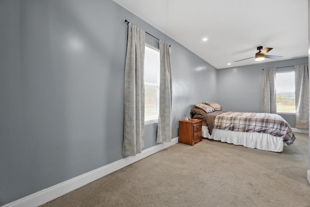 bedroom featuring multiple windows, light colored carpet, and ceiling fan