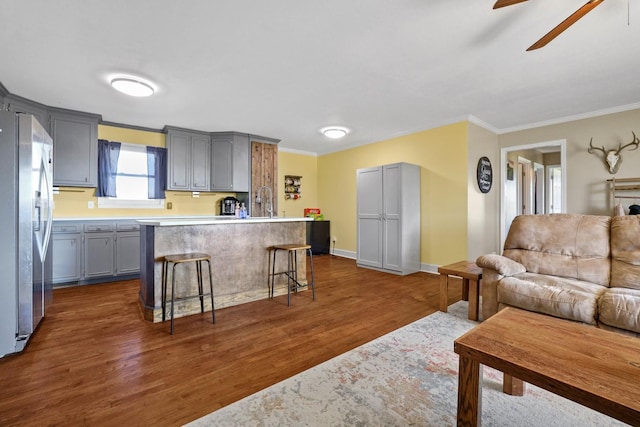 kitchen featuring a center island, gray cabinets, stainless steel fridge, and a breakfast bar