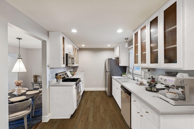 kitchen with pendant lighting, sink, stainless steel appliances, dark hardwood / wood-style floors, and white cabinets