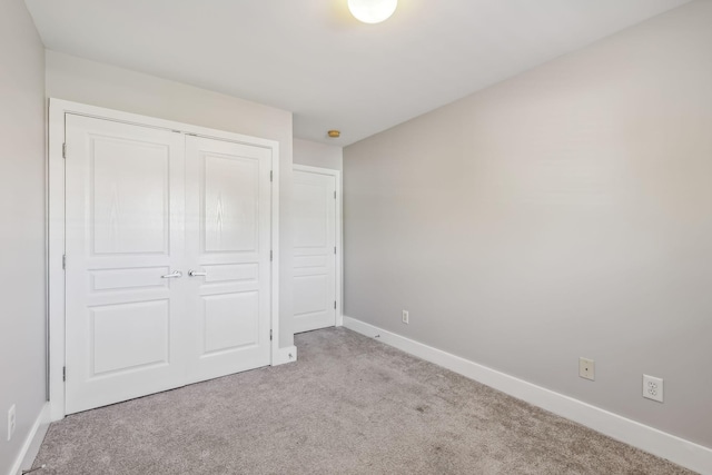 unfurnished bedroom with light carpet and a closet