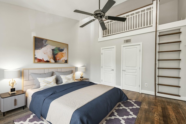 bedroom with ceiling fan, a towering ceiling, dark hardwood / wood-style flooring, and a closet