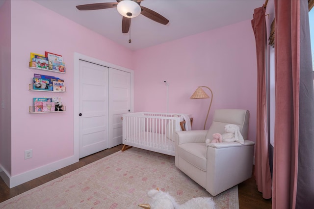 bedroom with wood-type flooring, a nursery area, a closet, and ceiling fan