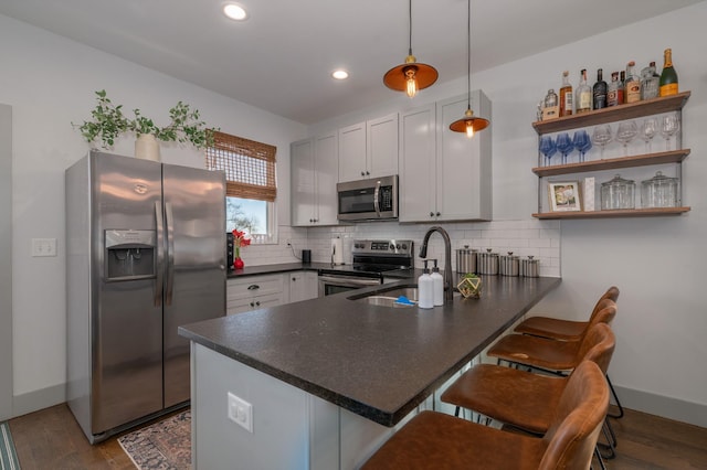 kitchen featuring stainless steel appliances, pendant lighting, a kitchen breakfast bar, and kitchen peninsula