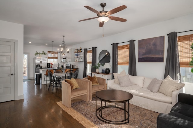 living room featuring dark hardwood / wood-style flooring and ceiling fan with notable chandelier